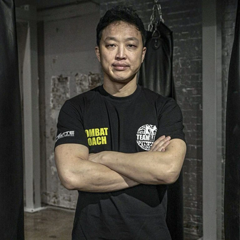 Phil, head Muay Thai coach, arms folded in the gym