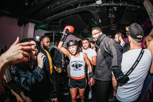 A fighter in a head guard walking out through the crowd at Backyard Bouts