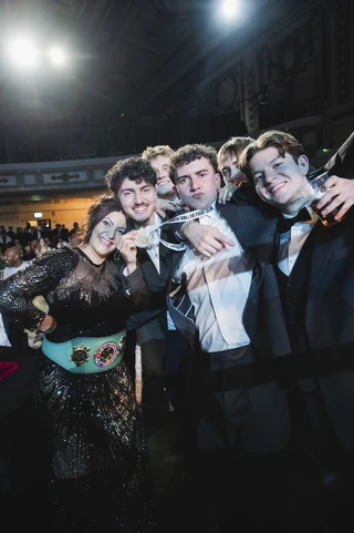 A group of supporters in black tie celebrating with a fighter