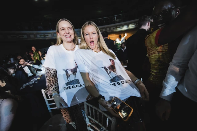 Two supporters in matching T-shirts cheering among the black tie tables
