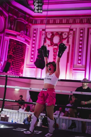 A fighter in pink shorts celebrating in the ring on fight night