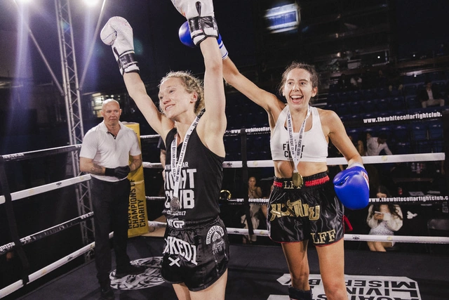 Two Muay Thai fighters raise their arms together in the ring after their bout