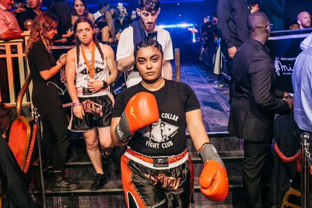 Shameen walks out to the ring in a White Collar Fight Club vest and orange gloves