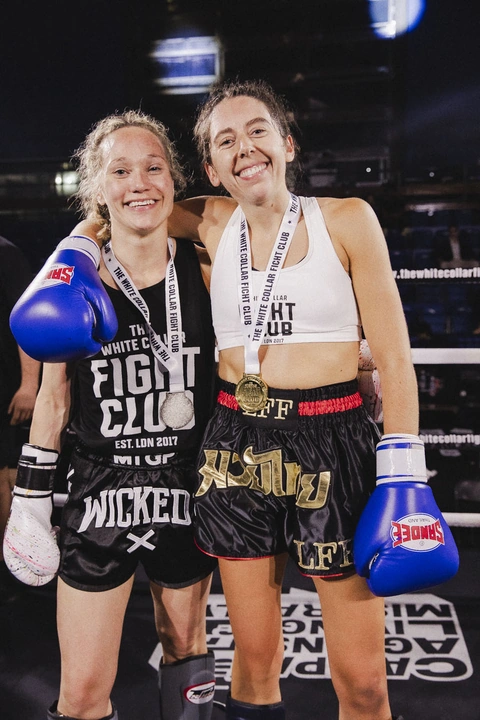 Two fighters with medals pose together in the ring after their bouts