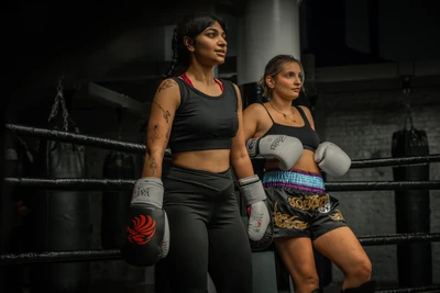 Two Muay Thai fighters in gloves and Thai shorts by the ring at Gymbox