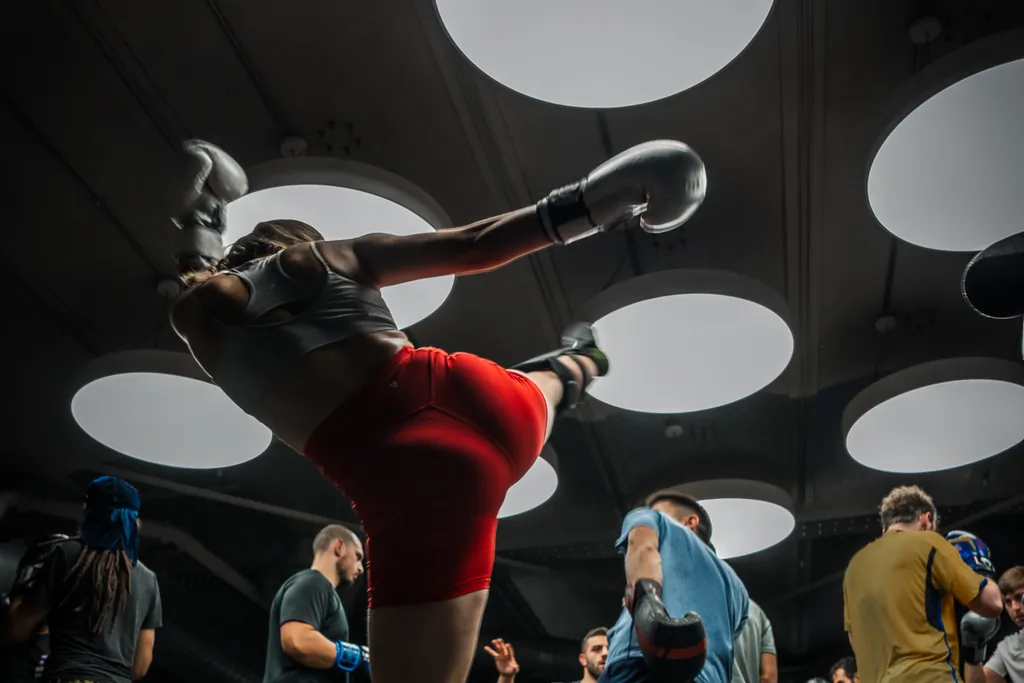 A fighter in red shorts throwing a high kick during a Muay Thai session at Gymbox
