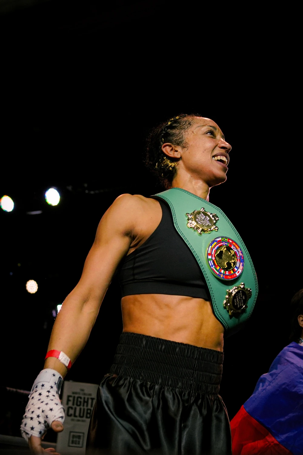 A fighter walking out wearing her winner's belt