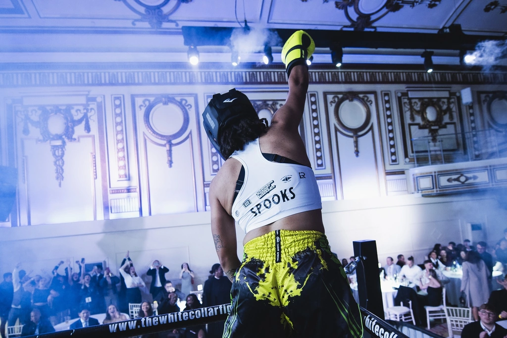 A fighter on the ropes saluting the black tie tables at a past fight night