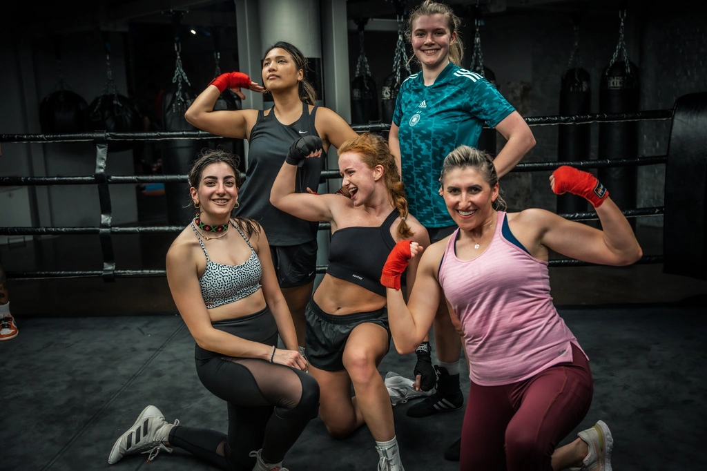 Five women from fight camp flexing and laughing in the gym