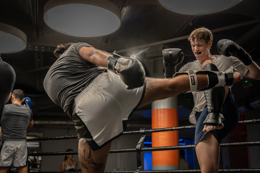 Two men practising kicks on the pads in a Muay Thai class
